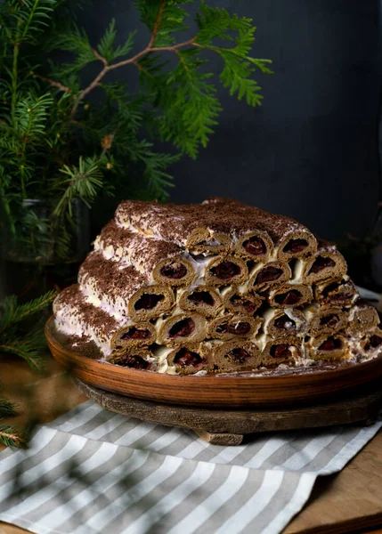 Monastic hut pie. Homemade cakes, sweet cake with cherry filling and cream. Collected from tubes, dough is rolled. Cake on the table. Festive food for dessert. — Stock Photo, Image