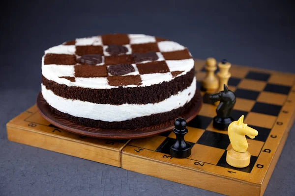 Svampkaka med smörkräm. Tårta i form av ett schackbräde. En gåva till en schackspelares dag. Tårta med chokladkakor och vit pudding. — Stockfoto