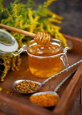 Arı poleni tanecikleri. Tahta masada taze bal. Yaşam arısı ürün geçmişi. Küçük cam kavanozlu ahşap kaşık. Çevre yemeği. Seçici odak, boşluğu kopyala.