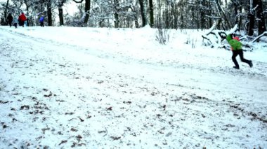 Ukrayna, Kyiv - 15 Ocak 2021: İnsanlar kar tepesinde kayıyor. Kışın karlı bir günde plastik bir kızakla kayan çocuklar. Mutlu bir çocukluk. Dışarıda kar yağıyor. Tatil eğlencesi