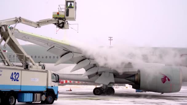 Украина, Борисполь - 12 февраля 2021 года: Аэропорт зимой. Обслуживание самолетов - погрузка багажа. Аэродинамика. Снег на подиуме. Пассажирский самолет Qatar Airlines A7-ALW AIRBUS A350-900 — стоковое видео