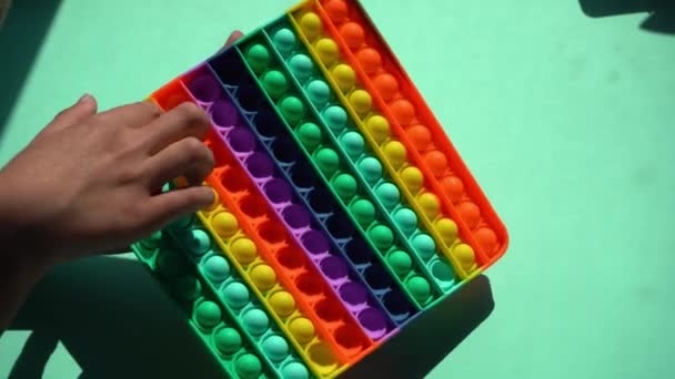 Helles Silikon gestreiftes Spielzeug Big Pop It. Kind spielt mit Regenbogen Pop es, drückt die Blasen mit den Fingern, Nahaufnahme von oben. Neues Antistress-Spielzeug für Kinder und Erwachsene. Popit-Spieler — Stockvideo