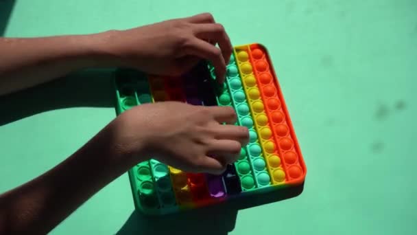 Giocattolo a strisce in silicone luminoso Big Pop It. Ragazzo che gioca con l'arcobaleno pop, premendo le bolle con le dita, primo piano vista dall'alto. Nuovo giocattolo antistress per bambini e adulti. Popit gamer — Video Stock