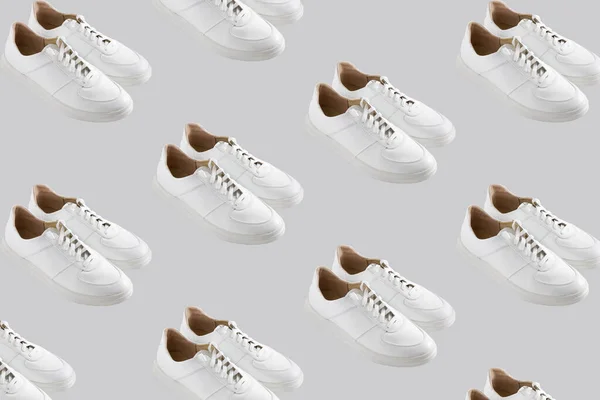 グレーの背景にホワイトのスニーカーパターン 靴は快適でカジュアルなものです 靴屋の背景 新しい靴のペア — ストック写真