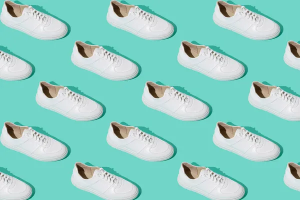 ミントブルーの背景にホワイトのスニーカーパターン 靴は快適でカジュアルなものです 靴屋の背景 新しい靴のペア — ストック写真