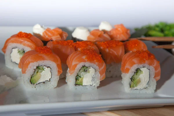 Salmon sushi set. Sushi roll Philadelphia with red fish, salmon, red caviar. Roll with soft avocado and cream cheese under a layer of massago caviar. Classic sushi. Food background.