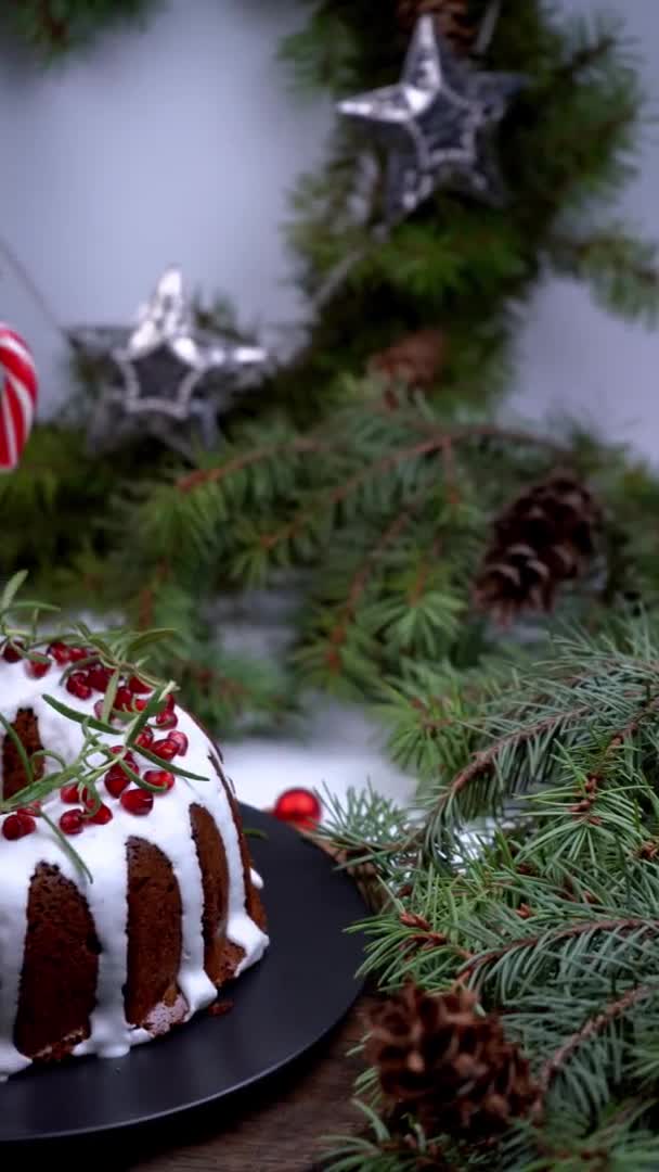 Christmas food. Round pie with white icing. Cupcake with a hole in the middle with pomegranate. Spruce branches on the table. Still life. Sweet pastries, desserts and treats for the new year. — Stock Video