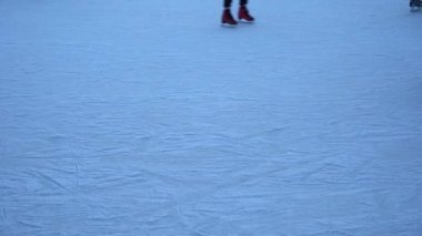 Kışın buz pateni pistinde. İnsanlar paten kayıyor. Patenler buzda kayar. Buz pateni kış sporu ve eğlencedir. Kadınlar, çocuklar, erkek bacakları....