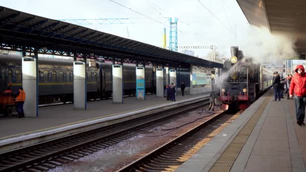 Ucrânia, Kiev - 7 de janeiro de 2022: O trem retro fuma na plataforma da estação ferroviária central. Velha locomotiva a vapor na plataforma. Emblema da Ucrânia. O fumo sai da chaminé. — Vídeo de Stock