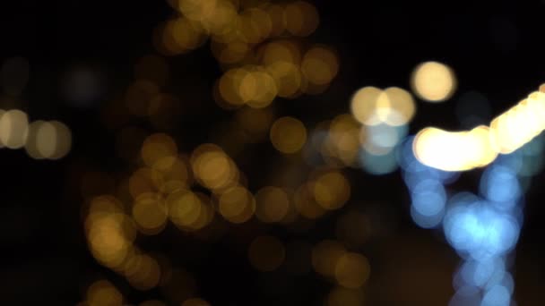 Bokeh από φώτα γιρλάντες. Θολή απαλή εστίαση. Η γιρλάντα αναβοσβήνει. Τα φώτα της πόλης τη νύχτα. Χριστουγεννιάτικη διάθεση. — Αρχείο Βίντεο