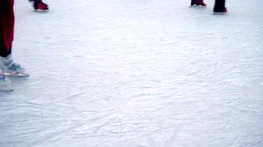 Kışın buz pateni pistinde. İnsanlar paten kayıyor. Patenler buzda kayar. Buz pateni kış sporu ve eğlencedir. Kadınlar, çocuklar, erkek bacakları....