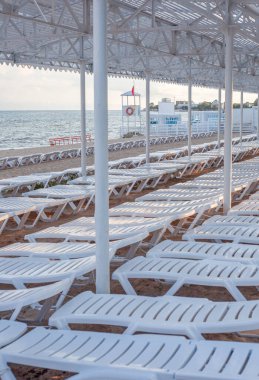 Yaz tatili konsepti. Deniz kıyısındaki bir sahilde iki güneş pansiyonu. Güneşli bir gün. Rahatlayın ve tatile çıkın. Yukarıdan yatak manzarası. Boş tatil köyü