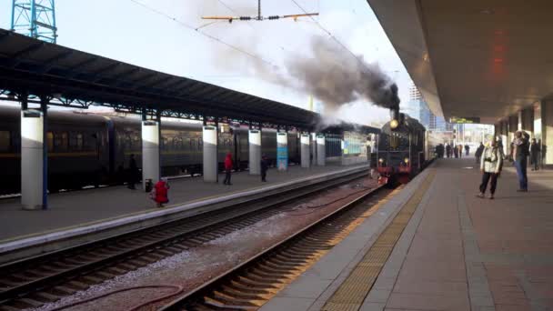 Oekraïne, Kiev - 7 januari 2022: Retro-trein rookt op het perron van het centraal station. Oude stoomlocomotief op het perron. Embleem van Oekraïne. Er komt rook uit de schoorsteen.. — Stockvideo