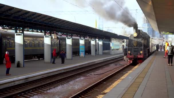 Ukraine, Kiev - January 7, 2022: Retro train smokes on the platform of the central railway station. Old steam locomotive on the platform. Emblem of Ukraine. Smoke comes out of the chimney. — Stock video