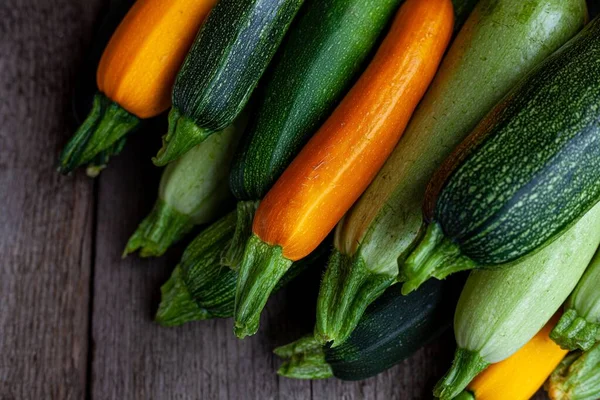 Una serie di zucchine multicolori giallo, verde, bianco, arancione sul tavolo primo piano. Esperienza alimentare. Zucca appena raccolta, zucca estiva tagliata. Ho raccolto zucchine verdi. Natura morta in cucina — Foto Stock