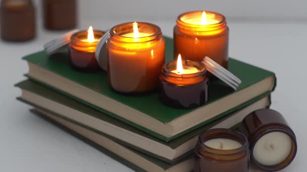 Een set van verschillende aroma kaarsen in glazen potten op een witte achtergrond. Handgemaakte geurkaarsen. Soja kaarsen branden in een jar.Wax en paraffine in een pot — Stockvideo