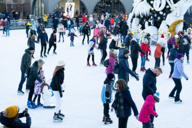 Kışın buz pateni pistinde. İnsanlar paten kayıyor. Patenler buzda kayar. Buz pateni kış sporu ve eğlencedir. Kadınlar, çocuklar, erkek bacakları....