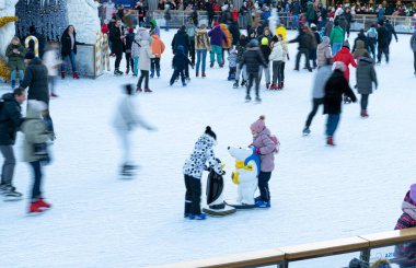 Kışın buz pateni pistinde. İnsanlar paten kayıyor. Patenler buzda kayar. Buz pateni kış sporu ve eğlencedir. Kadınlar, çocuklar, erkek bacakları....