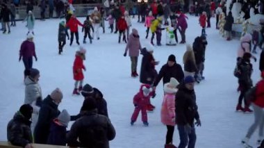 Kışın buz pateni pistinde. İnsanlar paten kayıyor. Patenler buzda kayar. Buz pateni kış sporu ve eğlencedir. Kadınlar, çocuklar, erkek bacakları....