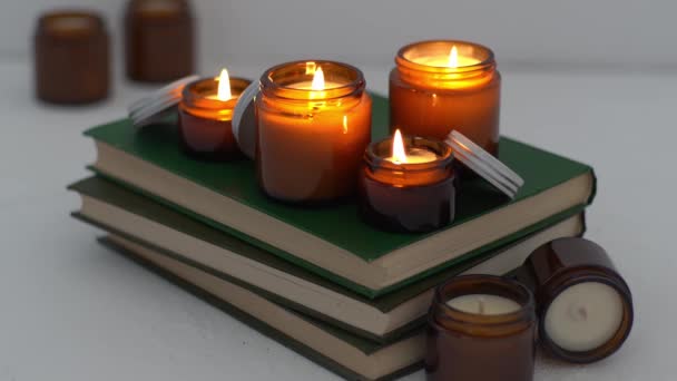 Un ensemble de différentes bougies aromatiques dans des bocaux en verre sur un fond blanc. Bougie artisanale parfumée. Les bougies de soja brûlent dans un pot. Cire et paraffine dans un pot — Video