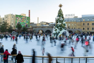 Kışın buz pateni pistinde. İnsanlar paten kayıyor. Patenler buzda kayar. Buz pateni kış sporu ve eğlencedir. Kadınlar, çocuklar, erkek bacakları....
