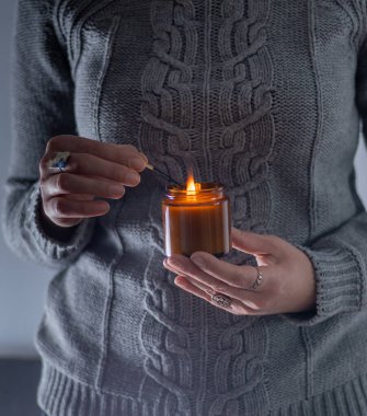 Elinde bir soya mumu tut ve yak. Kavanozda mum. Aromatheramia. Aroma mumu.