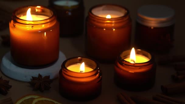 Velas aromáticas en frascos de vidrio marrón. La vela arde en la oscuridad. Aromaterapia, romance y relajación en el spa. Velas perfumadas y de soja arden por la noche. Cera y parafina en un frasco — Vídeo de stock