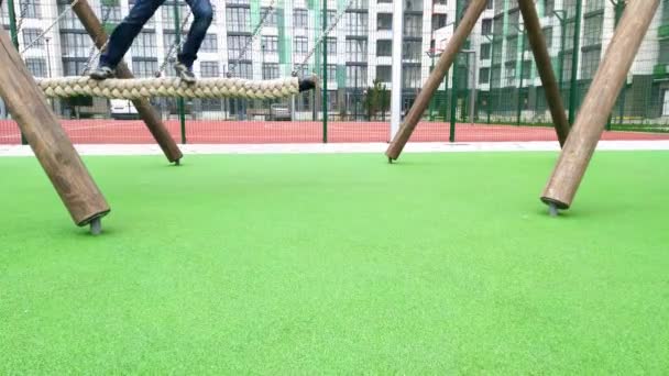 Swing on chains. Childrens legs ride on a rope. Child on the playground. Activity. Skate in the courtyard of a multi-storey building. Rope in the form of a pigtail. Play in the yard and garden — ストック動画