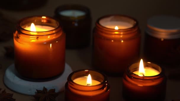 Aromatické svíčky v hnědých sklenicích. Svíčka hoří ve tmě. Aromaterapie, romantika a relaxace v lázních. Vonné a sójové svíčky hoří v noci. Vosk a parafín ve sklenici — Stock video