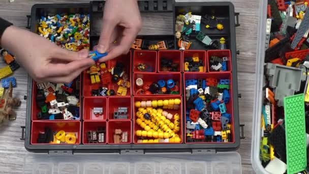Lego. Oyuncak üreticisi çocuklar. Bir sürü renkli detay. Oyun ve inşaat için bloklar ve tuğlalar. Eğitici oyuncak. Lego figürleri. Sıralama ve depolama. Oynayın. Kyiv, Ukrayna - 30 Mart 2022. — Stok video