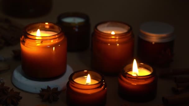 Velas aromáticas en frascos de vidrio marrón. La vela arde en la oscuridad. Aromaterapia, romance y relajación en el spa. Velas perfumadas y de soja arden por la noche. Cera y parafina en un frasco — Vídeo de stock