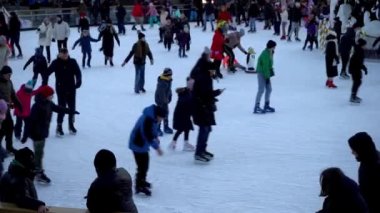Kışın buz pateni pistinde. İnsanlar paten kayıyor. Patenler buzda kayar. Buz pateni kış sporu ve eğlencedir. Kadınlar, çocuklar, erkek bacakları....