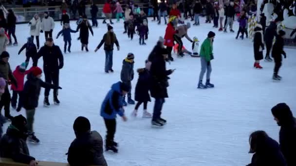 Patinoire en hiver. Les gens patinent. Les patins roulent sur glace. Le patinage sur glace est un sport d'hiver et de divertissement. Femmes, enfants, hommes jambes vont. — Video