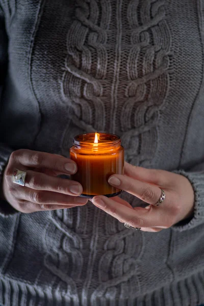 Enciende y sostén una vela de soja en tus manos. Vela en un frasco. Aromateramia. Vela de aroma. — Foto de Stock