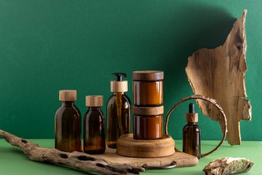 Ahşap kapaklı kozmetik ürünleri için cam kahverengi kaplar. Krema, damla şişesi ve losyon. Yeşil arka plan. İlgi ve güzellik. Şişeler.