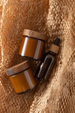 Kozmetik ve kremler için konteynır. Ahşap kapaklı cam kahverengi kavanoz. Bej arka plan. Tek renkli konsept. Etiket için bir yer. Krema kavanozları.