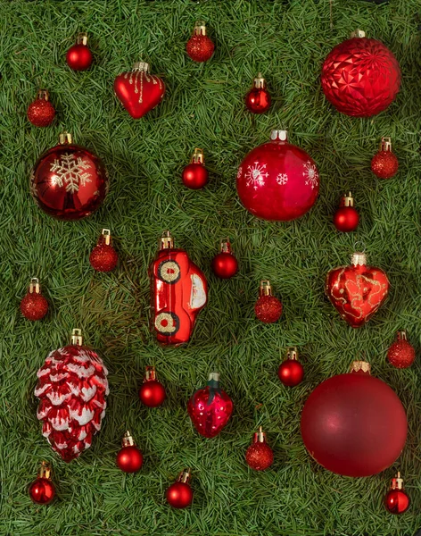 クリスマスツリーの針の緑の背景に異なる赤いクリスマスのおもちゃのセット 赤いボール 装飾品と装飾品 新年のコンセプト — ストック写真