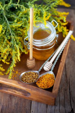 Arı poleni tanecikleri. Tahta masada taze bal. Yaşam arısı ürün geçmişi. Küçük cam kavanozlu ahşap kaşık. Çevre yemeği. Seçici odak, boşluğu kopyala.