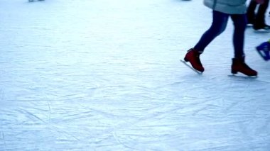 Kışın buz pateni pistinde. İnsanlar paten kayıyor. Patenler buzda kayar. Buz pateni kış sporu ve eğlencedir. Kadınlar, çocuklar, erkek bacakları gider. Noel zamanı. Artistik patinaj egzersizi yakın çekim..