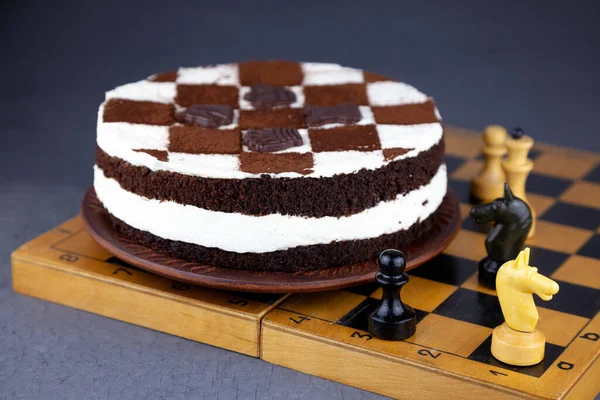 Sponge cake with butter cream. Cake in the form of a chessboard. A gift for the day of a chess player. Cake with chocolate cakes and white pudding. Appetizing dessert. Place for text.