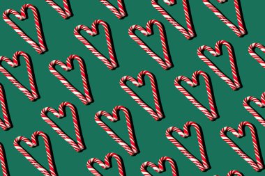 Yeşil arka planda kırmızı ve beyaz lolipopların deseni. Noel konsepti. Kalp şeklinde şekerlemeler. Gıda arkaplanı.