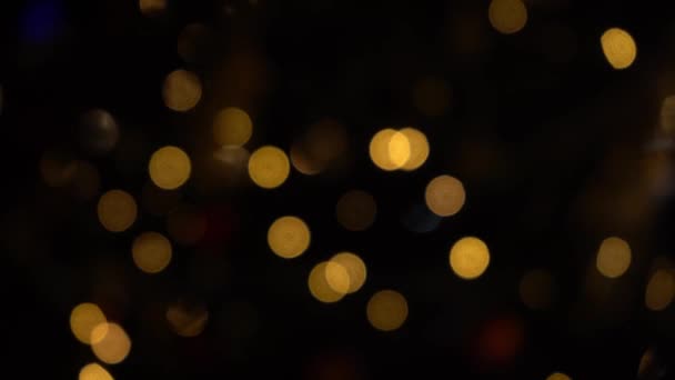 ガーランドのライトのボケ 焦点をぼかした ガーランドが点滅している 夜の街の灯 クリスマス気分 要約ぼやけたクリスマスツリーのちらつき 冬休みのコンセプト — ストック動画