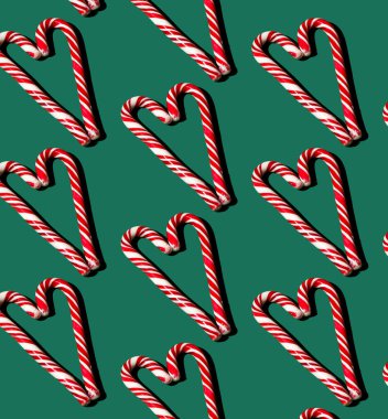 Yeşil arka planda kırmızı ve beyaz lolipopların deseni. Noel konsepti. Kalp şeklinde şekerlemeler. Gıda arkaplanı.