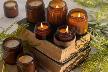 A set of different aroma candles in brown glass jars. Scented handmade candle. Soy candles are burning in a jar. Aromatherapy and relax in spa and home. Fire in brown jar. Yellow flowers