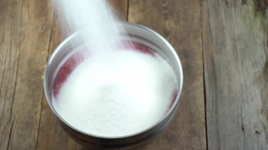Sip sugar into a bowl with red currants. Currant with sugar. Prepare jam.