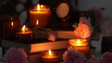 A set of different aroma candles in brown glass jars and flowers. Scented handmade candle. Soy candles are burning in a jar. Aromatherapy and relax in spa and home. Fire in brown jar. Dark evening