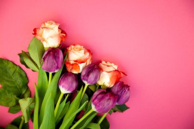 Bouquet of roses and tulips on a plain pink background. Layout for a greeting card. Spring concept. Copy space. Flowers top view. Tulip flower.