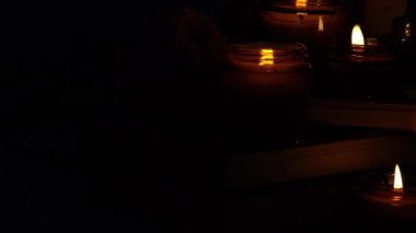 A set of different aroma candles in brown glass jars and flowers. Scented handmade candle. Soy candles are burning in a jar. Aromatherapy and relax in spa and home. Fire in brown jar. Dark evening