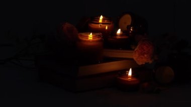 A set of different aroma candles in brown glass jars and flowers. Scented handmade candle. Soy candles are burning in a jar. Aromatherapy and relax in spa and home. Fire in brown jar. Dark evening