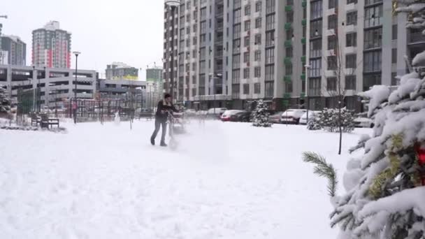 ウクライナ キエフ 2022年1月10日 冬の雪をクリアする 雪の日だ 手動ディーゼルトラクター雪清浄機 複数の中庭階建ての建物 男性清掃員とスノーブロワー 街路清掃員 — ストック動画